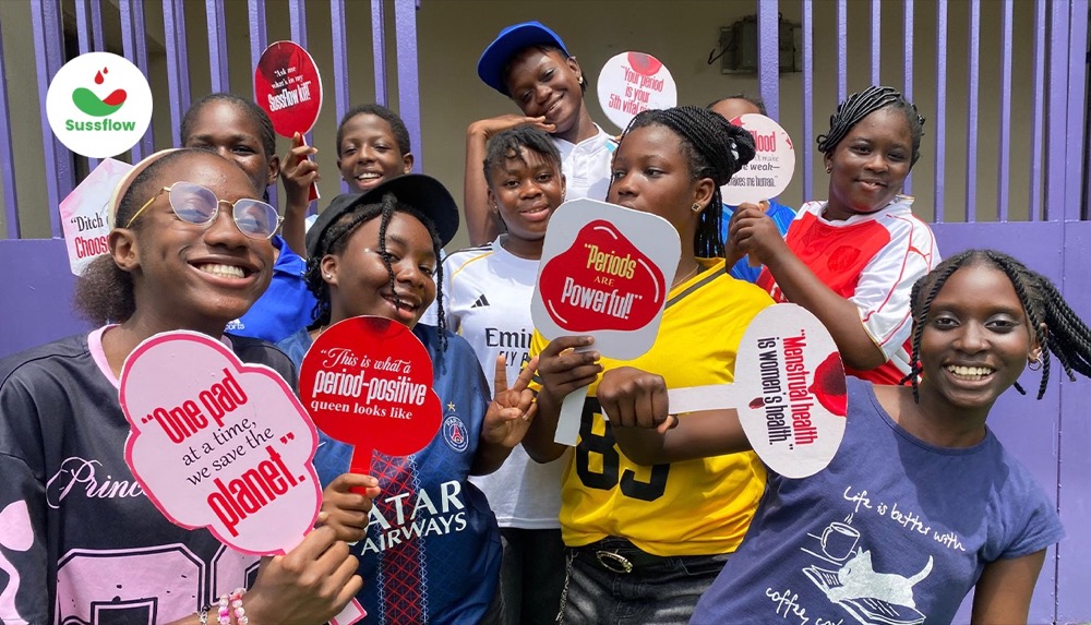 Smiling teenage girls holding period-positive signs such as “Periods are powerful”