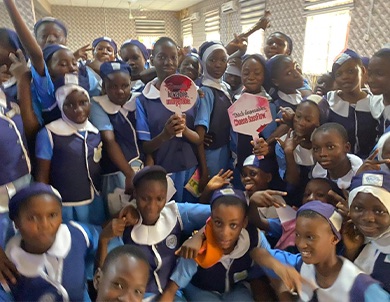 A classroom full of schoolgirls in blue uniforms cheering