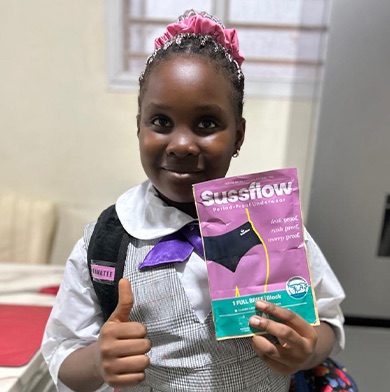 A young student giving a thumbs up while holding a Sussflow period pant